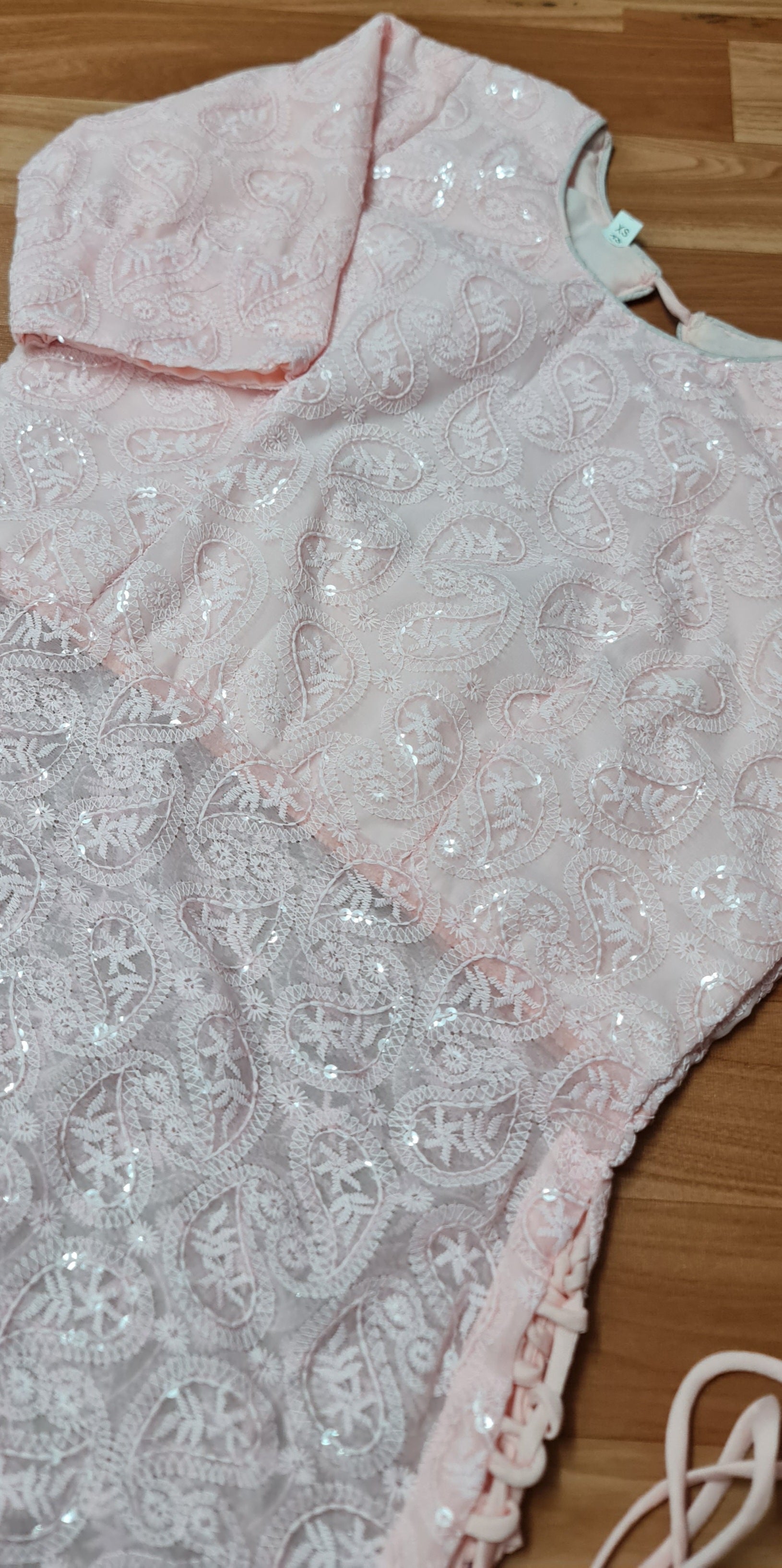 Simple and elegant: A long, flowing peach kurti in soft georgette fabric with delicate side tassels.