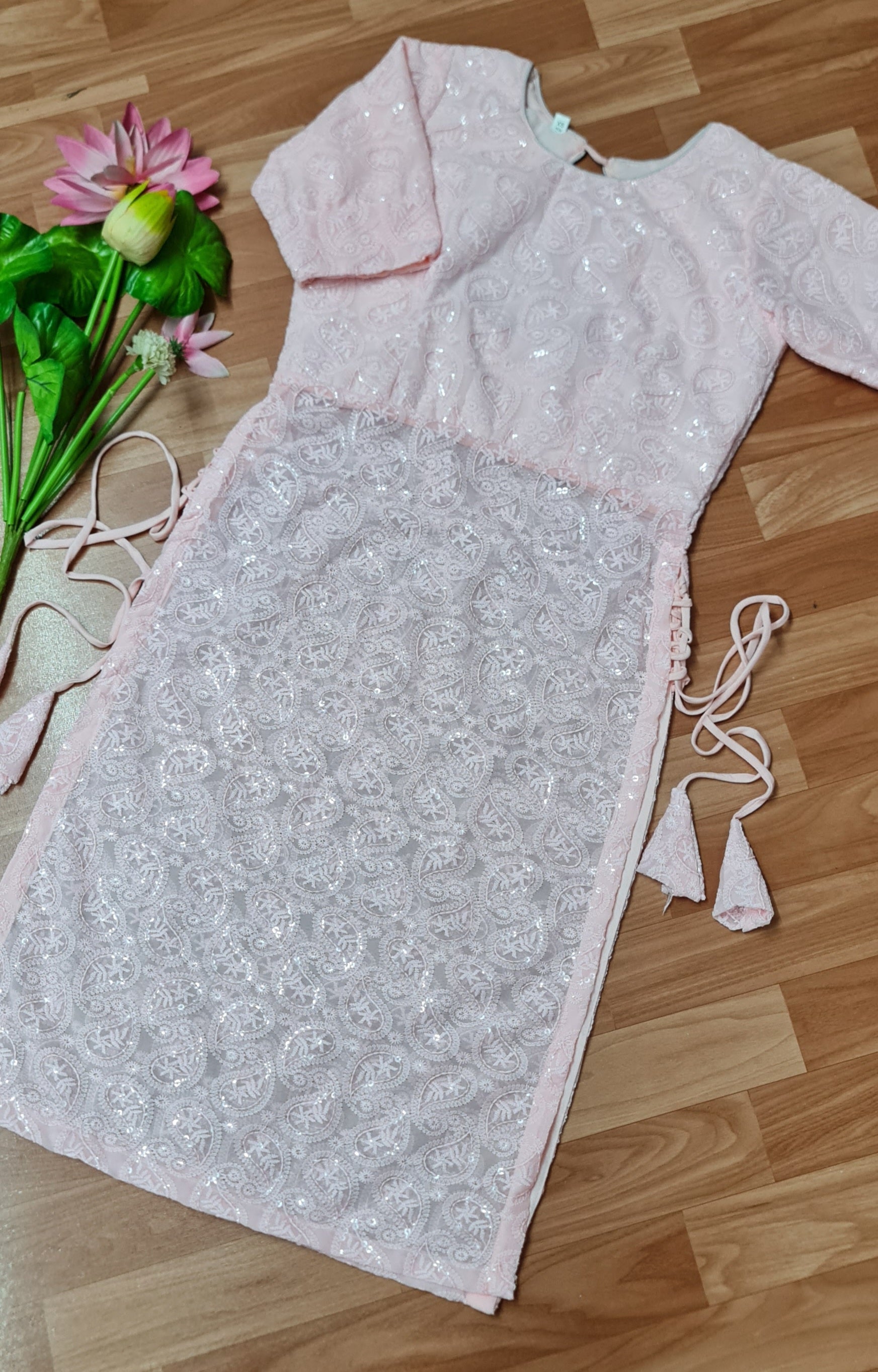 Simple and elegant: A long, flowing peach kurti in soft georgette fabric with delicate side tassels.